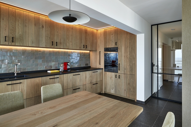 moderne keuken, open keuken, ingerichte keuken, houten keuken, zwarte keuken, keuken met houtaccenten, keuken met eiland, kookeiland, keuken met bar, keuken met barkrukken, luxe keuken, stijlvolle keuken, lichtrijke keuken, keuken met groot raam, keuken met terras, keuken met tuinzicht, open leefruimte, modern interieur, strak interieur, hedendaagse afwerking, keuken met ingebouwde toestellen, keuken met inbouwapparatuur, keuken met spoelbak, keuken met oven, instapklare woning, gerenoveerde woning