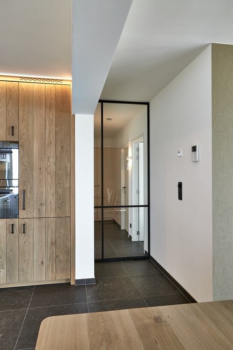 moderne keuken, open keuken, ingerichte keuken, houten keuken, zwarte keuken, keuken met houtaccenten, keuken met eiland, kookeiland, keuken met bar, keuken met barkrukken, luxe keuken, stijlvolle keuken, lichtrijke keuken, keuken met groot raam, keuken met terras, keuken met tuinzicht, open leefruimte, modern interieur, strak interieur, hedendaagse afwerking, keuken met ingebouwde toestellen, keuken met inbouwapparatuur, keuken met spoelbak, keuken met oven, instapklare woning, gerenoveerde woning